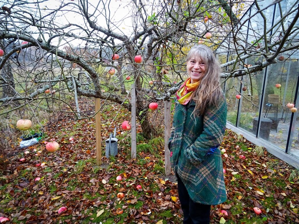 Eva Solhäll vid äppelträdet som växer och frodas i hälsoträdgården.
