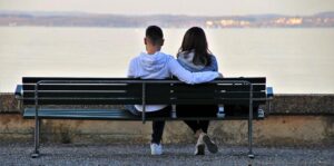 Två ungdomar som sitter på en bänk. Ansiktena mot havet. Fotograf: Pasja1000 från Pixabay