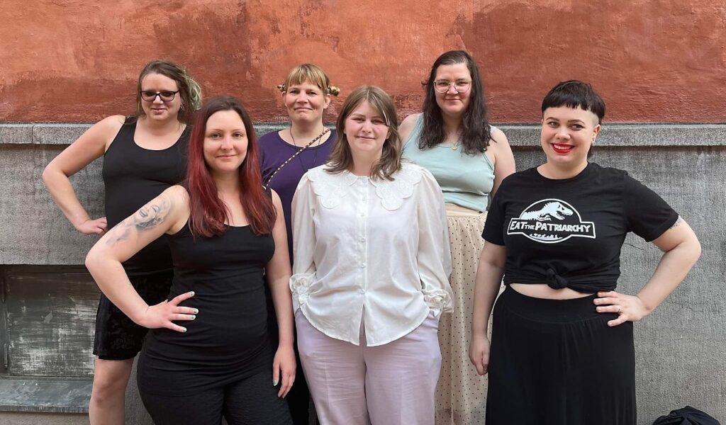 Gruppbild av deltagarna i projektet "Lyssna på oss". De står mot en grå och vit vägg.