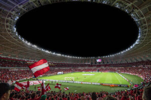 Fotbollsplan med supportrar. Österrikiska flaggor visas. Foto: Riccardo från Pexels.