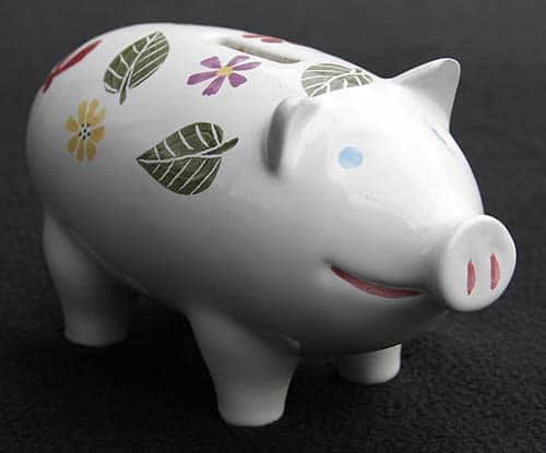 Vit spargris med gröna blad och en gul och en lila blomma.