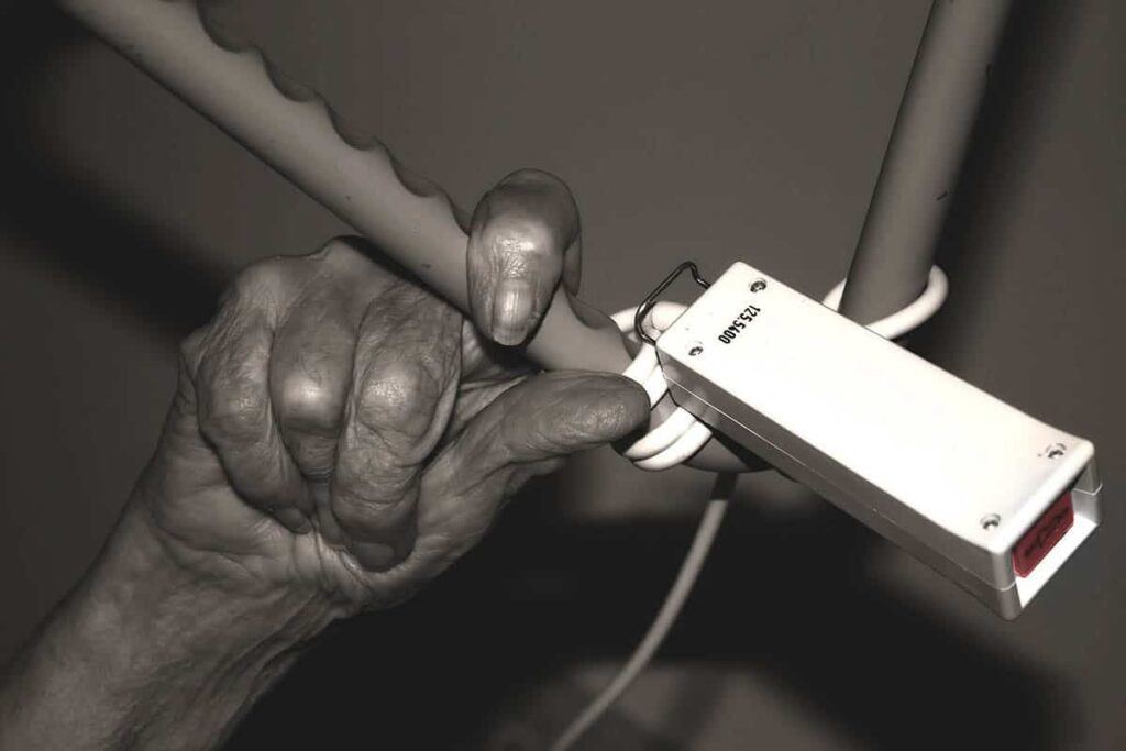 Gammal kvinnohand som greppar efter en nödklocka, antagligen på ett sjukhus. Foto: Geralt från Pixabay