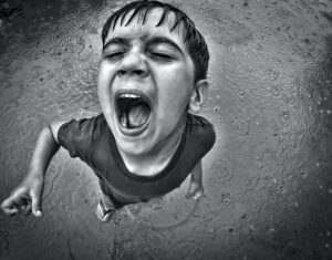 Barn som skriker i regn. Fotot taget uppifrån i svartvitt.