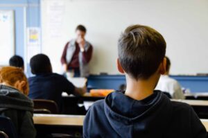 Pojke sitter i ett klassrum med lärare och andra elever