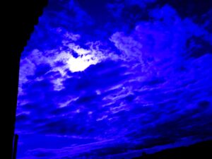 Blå himmel som visas som målade linjer mort svart bakgrund. Solen syns lysa fram på ett litet ställe. Foto. Linda Åkesson.