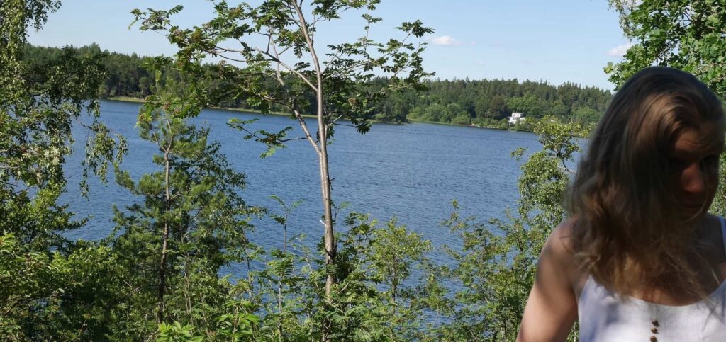 Linda Åkesson framför sjöutsikt med tallar.