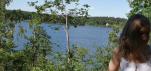 Linda Åkesson framför sjöutsikt med tallar.