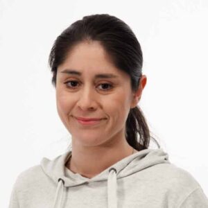 Porträtt av Maria Nilsson. Mörkbrunt hår. Mittbena och hästsvans. Vit träningsliknande tröja. Vitbakgrund.