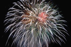 Vitt fyrverkeri med rött i mitten mot svart bakgrund.