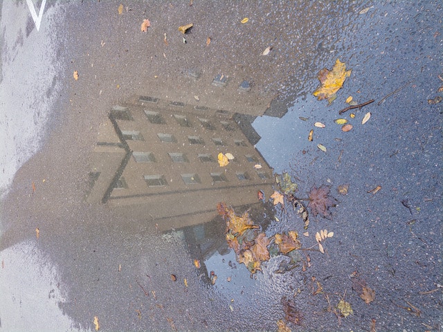 Bild på hus som speglas i vattenpöl