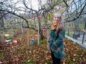Eva Solhäll vid äppelträdet som växer och frodas i hälsoträdgården.