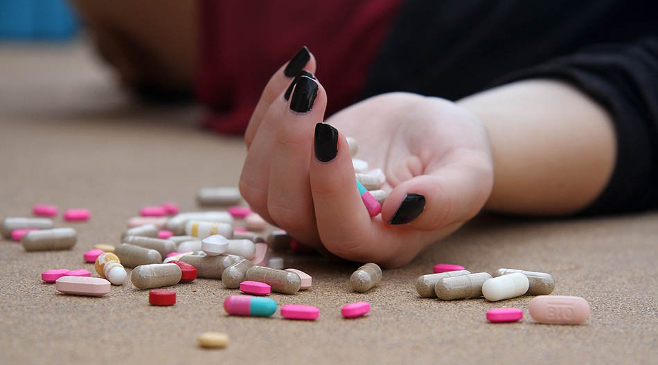 Kvinnohand med fullt av pilleri och vid sidan om. Foto: Hasty Words, Pixabay
