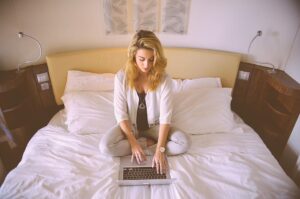 Ung kvinna med sin laptop i sängen i sovrummet. Foto: Stokpic från Pixabay