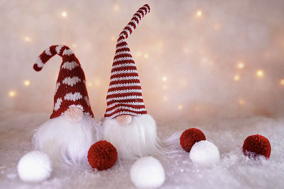 Två tomtar med stickade tomteluvor i stiliserad vit snö och stiliserade vita snöbollar. Foto: Susanne Jutzeler, Suji foto, Pixabay