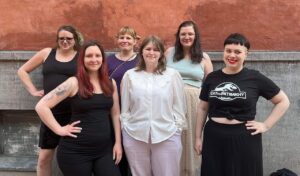 Gruppbild av deltagarna i projektet "Lyssna på oss". De står mot en grå och vit vägg.