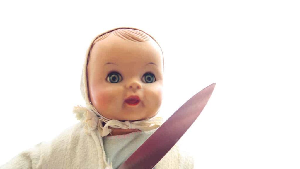 En babydocka som håller en vass kniv rätt upp i luften. Foto: Monica Atterberg