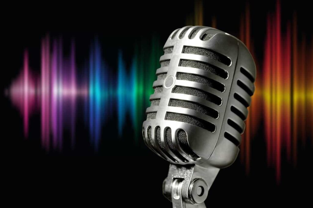 En silvrig mikrofon mot svart bakgrund. Ljudvågor i många färger syns också i bakgrunden. Foto: Stefan Schweihofer från Pixabay