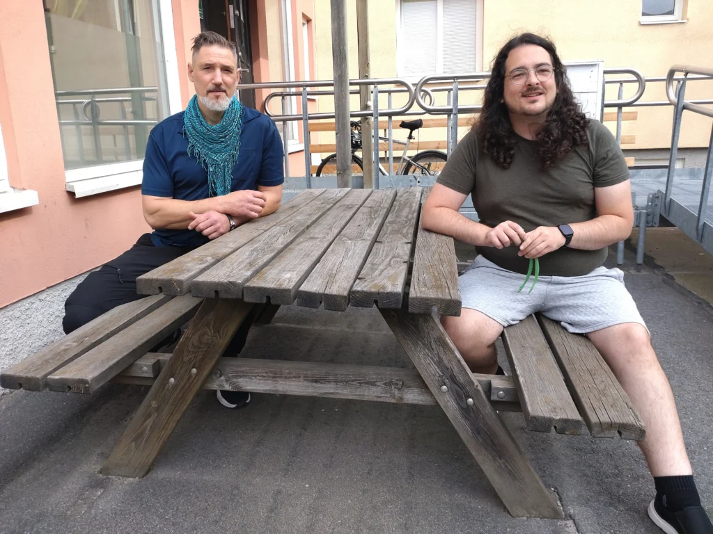 Henrik Brunnberg och Razvan Radu sitter vid ett bord och tittar in i kameran. Bägge är aktiva i Jag Gör Politik.