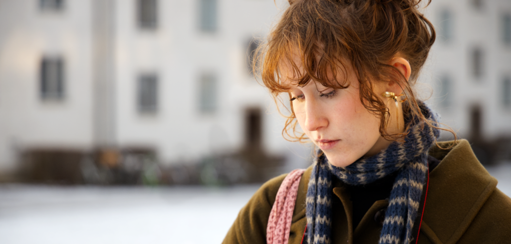 Ung kvinna utomhus i vintern skriver i Vox-Vigor block