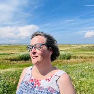 Pernilla Molnar, en kvinna i glasögon framför öppet landskap.