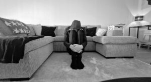 Man som sitter hopkurad framför en soffa