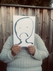 Person som gömmer sig bakom papper med tecknat ledset ansikte