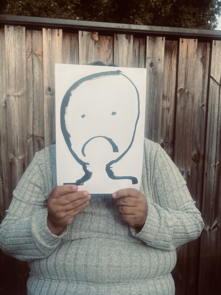 Person som gömmer sig bakom papper med tecknat ledset ansikte